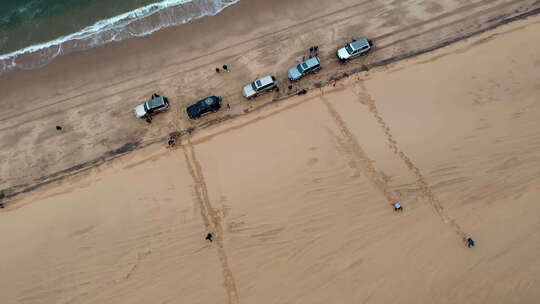 巨大沙丘旁边海滩上的汽车照片