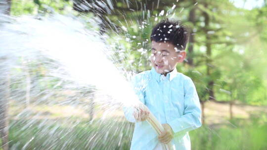 在公园里浇水的快乐男孩