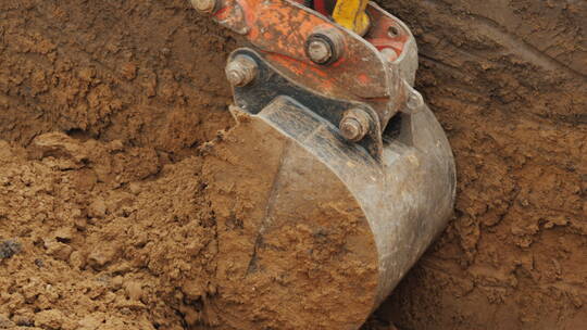 挖掘机铲斗铲起泥土并抬起