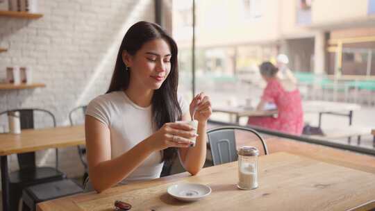 混血女人在咖啡馆餐厅的桌子上喝咖啡。