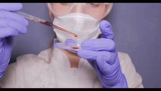 女性医学研究科学家在培养基中滴入有色液体