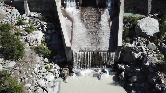 瑞士阿尔卑斯山一座石头水电站后的山间湍流瀑布，能源工业视频素材模板下载