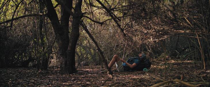 男子在大树旁躺在了背包上