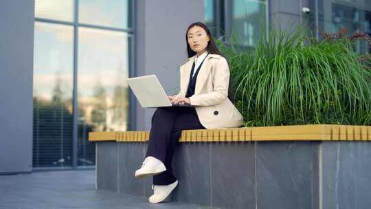 年轻的亚洲女商人远程工作，坐在现代办公室视频素材模板下载
