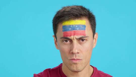 脸上画着委内瑞拉国旗的严肃男人