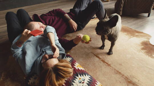 夫妻躺在地毯上和斗牛犬玩耍