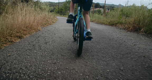 儿童男孩沿着田野在乡村道路上骑自行车积极的生活方式