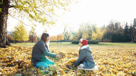 母亲和女儿在公园里扔秋叶