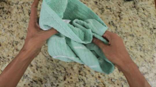 双手使用和折叠绿色毛巾，自上而下视图