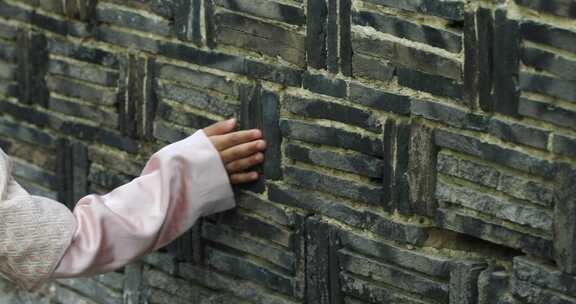 女孩用手触摸古墙砖