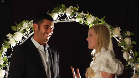 新娘和新郎在花拱门下欢笑