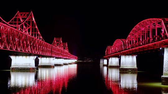 鸭绿江两座大桥夜晚红色灯光倒映在水面上