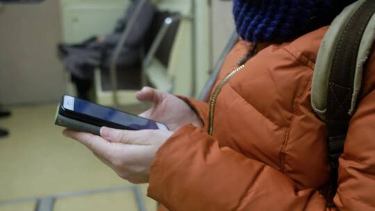 女乘客在地铁里使用手机。