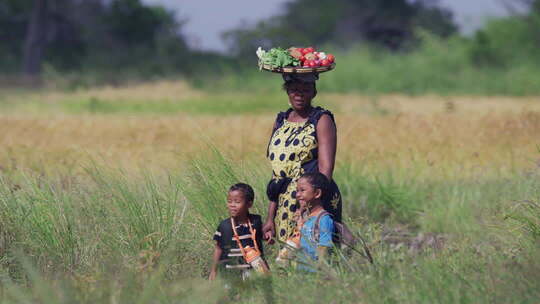 非洲女人头顶蔬菜篮子接孩子放学回家