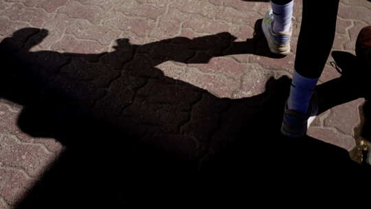 一个斜倚在纹理鹅卵石上的人的长影子在城市