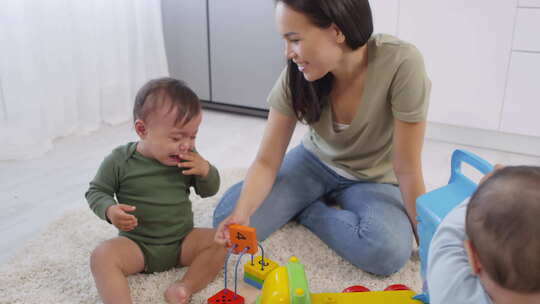 亚洲妈妈安慰哭泣蹒跚学步的孩子和兄弟姐妹