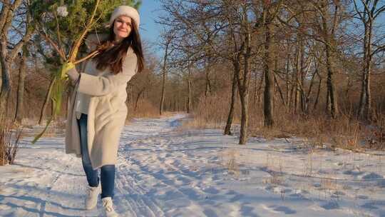 戴圣诞老人帽的年轻女子在雪林中携带圣诞树