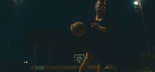 男人在黑夜里投掷篮球 