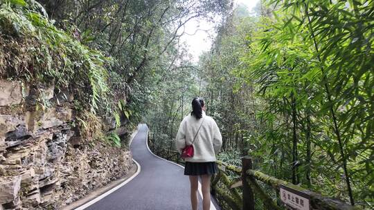 女子漫步于植被繁茂的山间小路