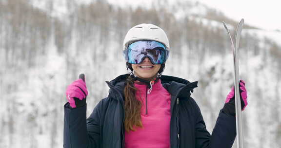 一个微笑的滑雪者在山里度假的肖像，在她身