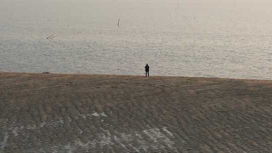 一个人走在夕阳照耀下的沙滩上