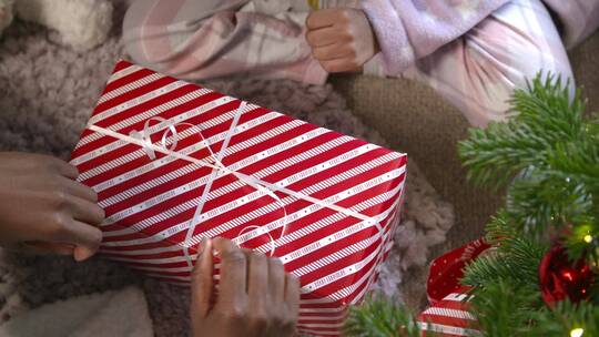 儿童在圣诞树旁拆礼物视频素材模板下载
