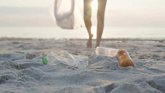 志愿者在海边捡起垃圾放进袋子里视频素材模板下载