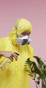 一个穿黄色防护服的人在给植物喷洒水竖屏