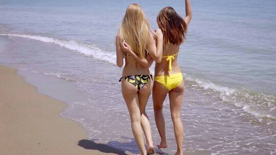 两个年轻女人沿海滩散步