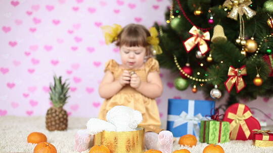 女孩在圣诞树旁吃糖果