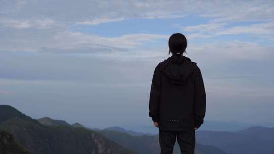 女性青年站在山顶看风景背影看远山感受自然