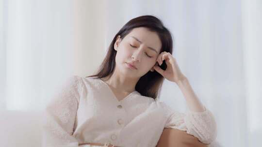 女性居家闭眼揉太阳穴画面