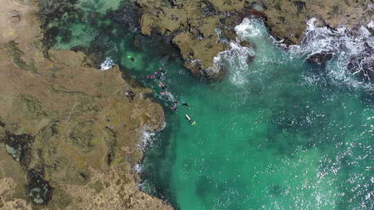 绿松石海水中浮潜游客上空的空中升起，岩石海岸