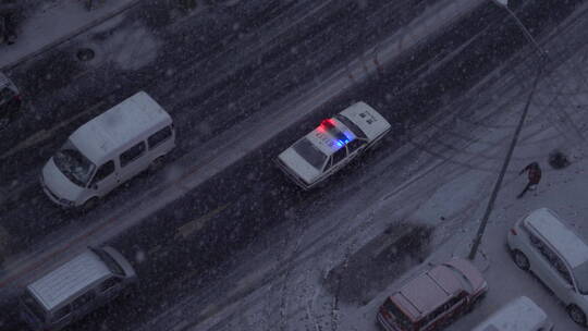 俯拍下雪天在路上行驶的警车