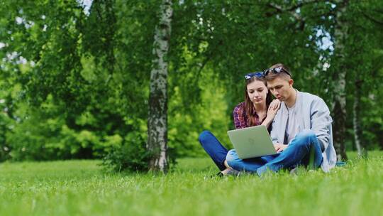 情侣在公园草地看笔记本视频素材模板下载