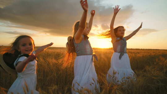 快乐的斯拉夫儿童女孩在夕阳下的农田小姐妹们在金色麦田上旋转