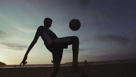 男孩傍晚沙滩踢球