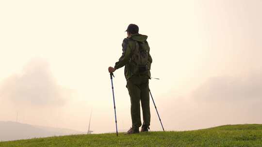 户外背包客手持登山杖站立草地