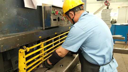 钢铁工厂的车间内工人操作机器冲压机床