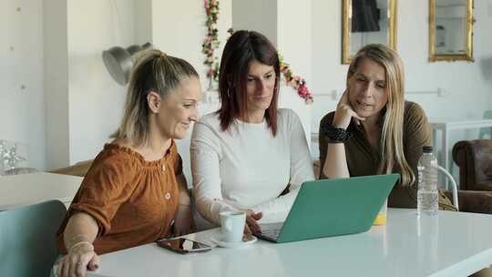 三个女人坐在咖啡店里一起使用笔记本电脑