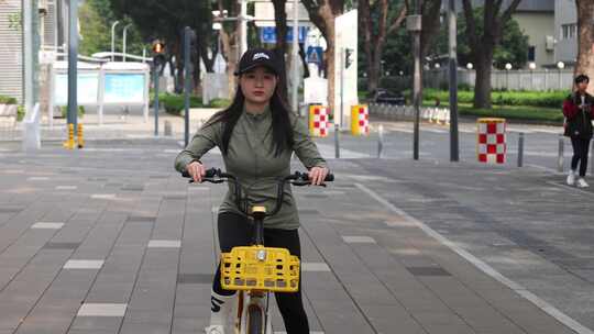 女子城市街道骑行共享单车 