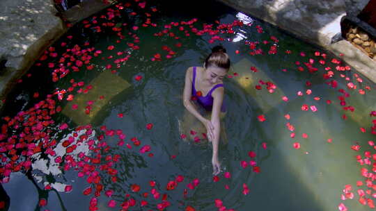 女子在花瓣覆盖的温泉中放松