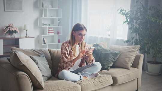 女人在家庆祝在智能手机上赢得在线游戏