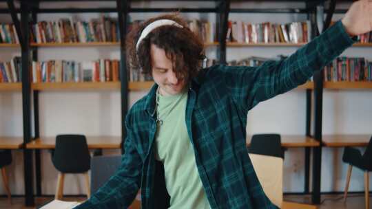 年轻的男学生在图书馆里用耳机听音乐和跳舞