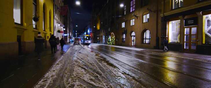 有轨电车在城市街道建筑物旁边的雪泥中行驶