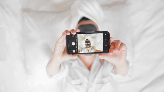 面膜女人躺在床上用手机拍照