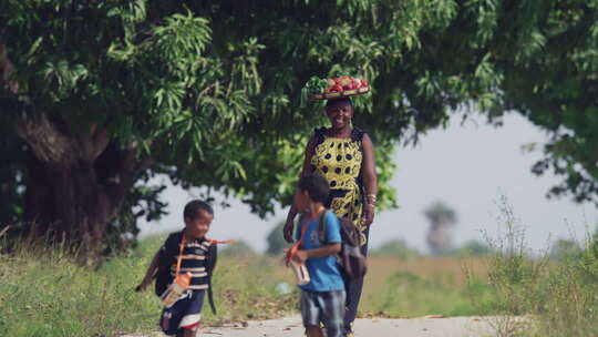 非洲女人头顶蔬菜篮子接孩子放学回家