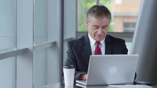 男人喝着咖啡在电脑前工作