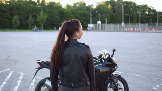 穿着皮衣马尾辫的女孩在镜头前摆姿势靠近黑色昂贵的“铁马”视频素材模板下载