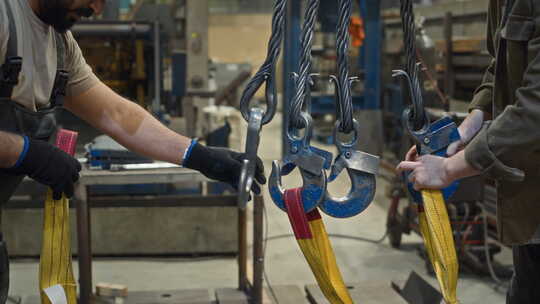 工厂工人从起重机吊钩上取下吊带